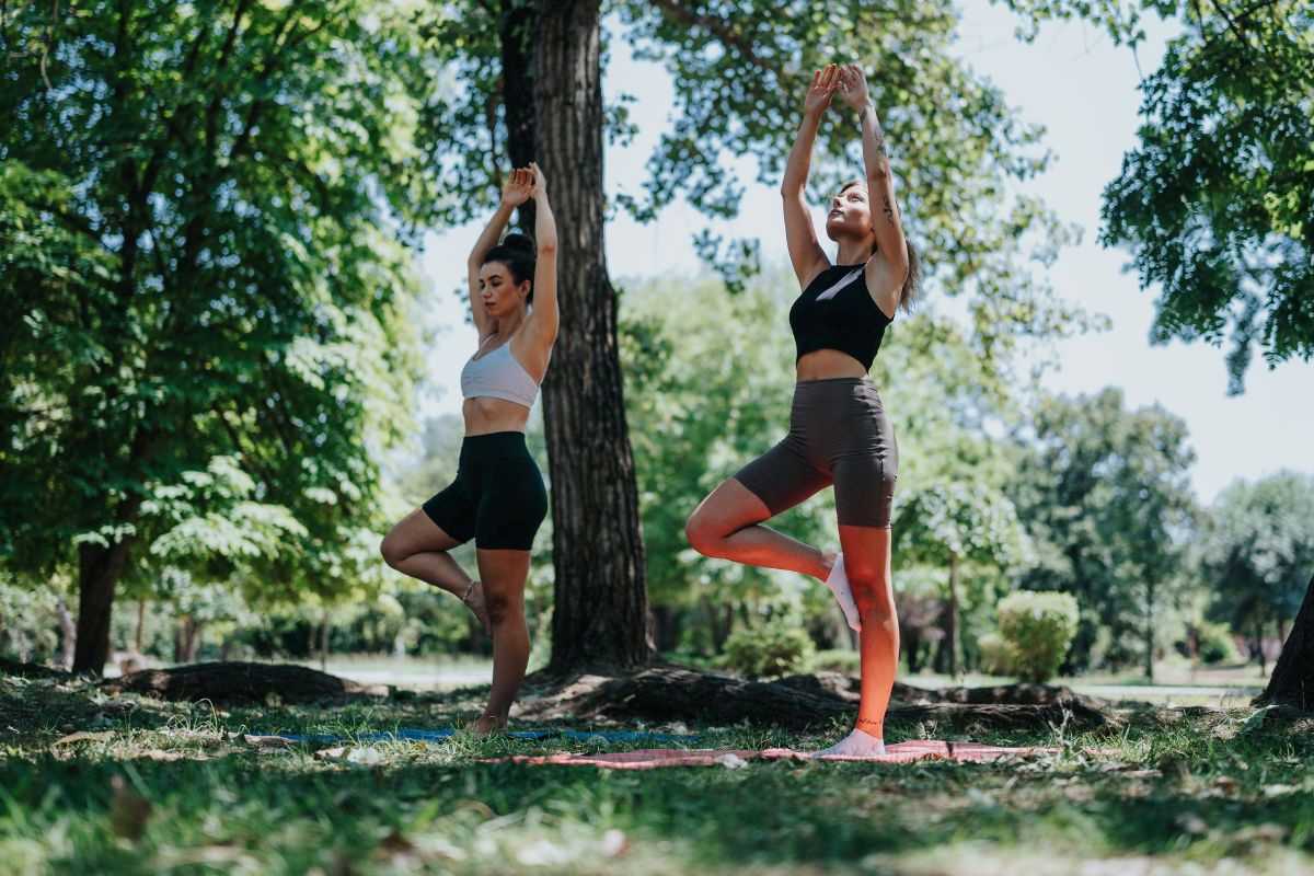 due ragazze praticano yoga all'interno di un bosco a contatto con la natura