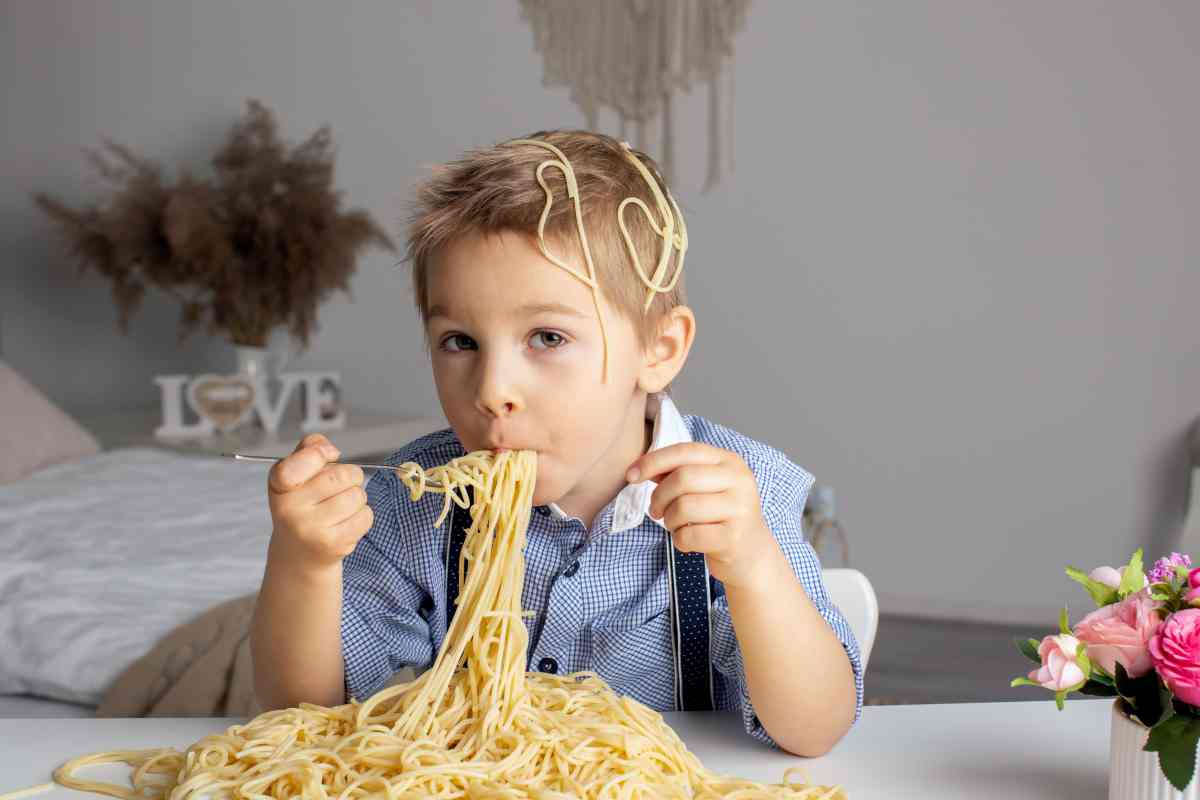 un bambino mangia un enorme piatto di pasta