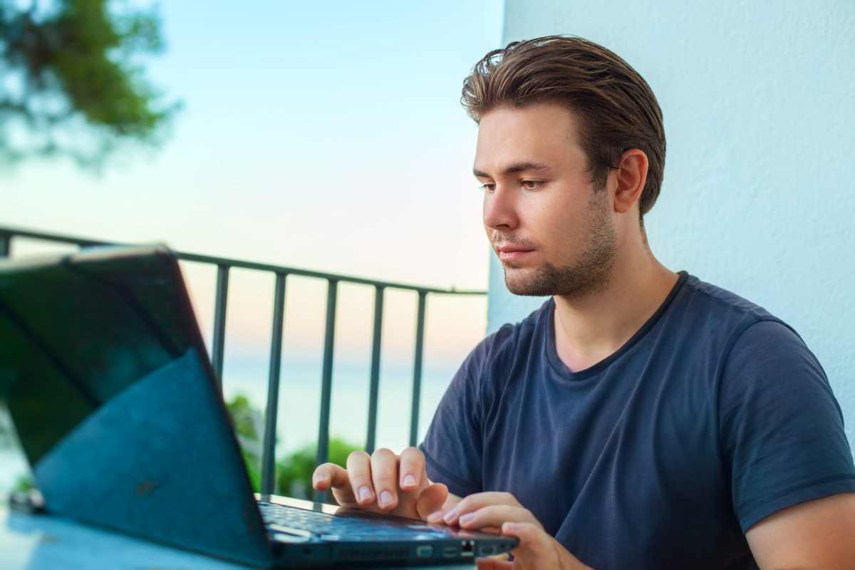 un uomo lavora al computer su una terrazza vista mare