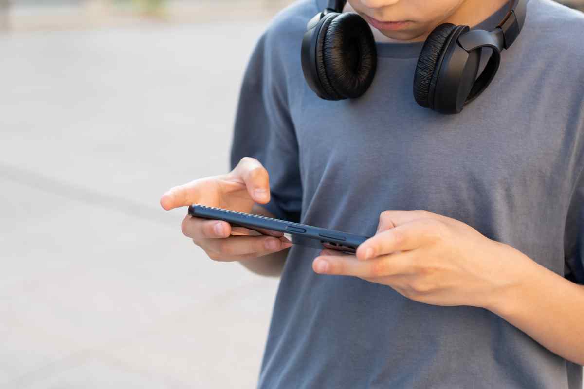 un ragazzino con gli occhi fissi sul telefono