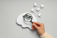 persona che punta una lente di ingrandimento su un cervello composto da puzzle che perde pezzi
