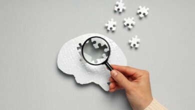persona che punta una lente di ingrandimento su un cervello composto da puzzle che perde pezzi