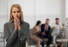 Ambiente di lavoro tossico in cui tre persone additano e parlano alle spalle di una collega