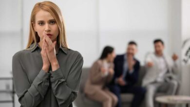 Ambiente di lavoro tossico in cui tre persone additano e parlano alle spalle di una collega