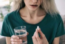 donna che tiene in mano un bicchiere d'acqua e una pastiglia di antidepressivi