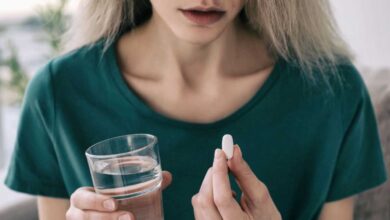 donna che tiene in mano un bicchiere d'acqua e una pastiglia di antidepressivi