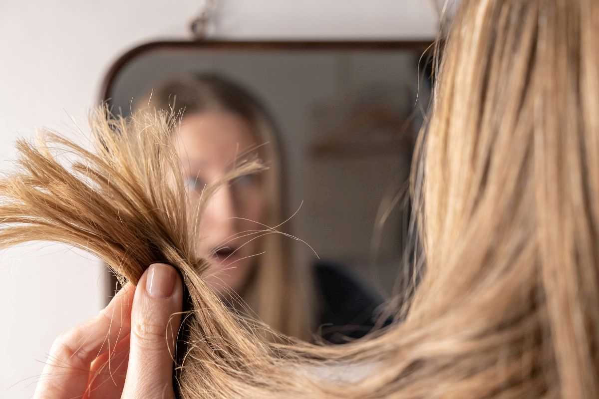 donna che si guarda le doppie punte di capelli danneggiati