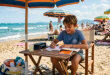 ragazzino che fa i compiti estivi sotto all'ombrellone in spiaggia