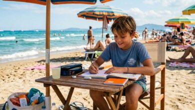 ragazzino che fa i compiti estivi sotto all'ombrellone in spiaggia