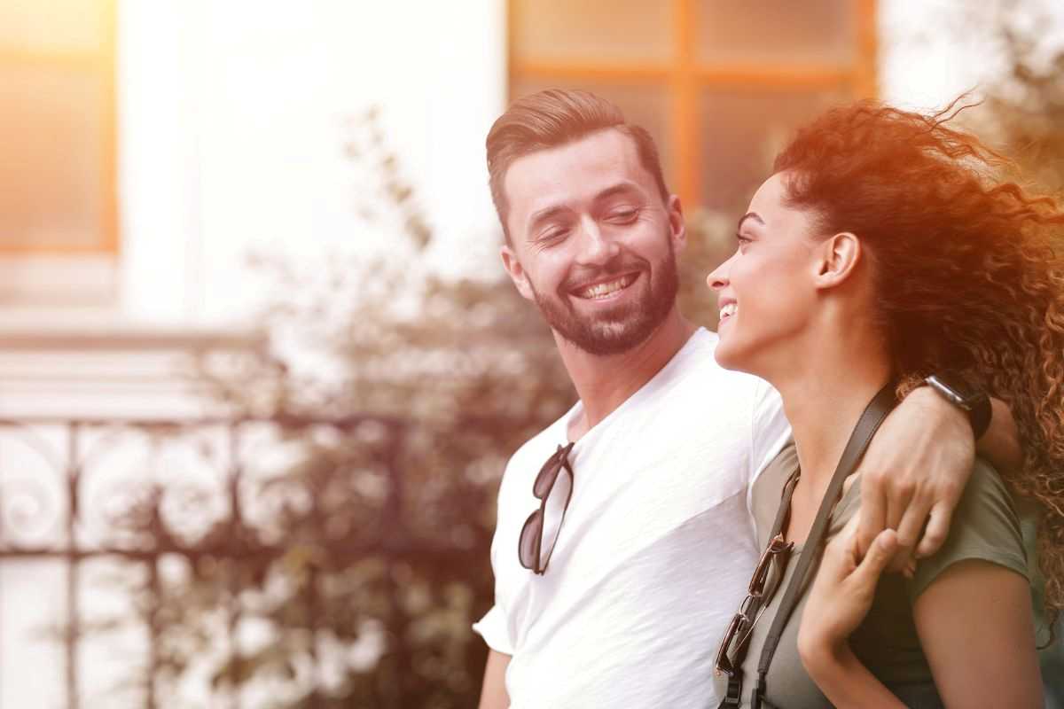 coppia di giovani che passeggia guardandosi e sorridendo