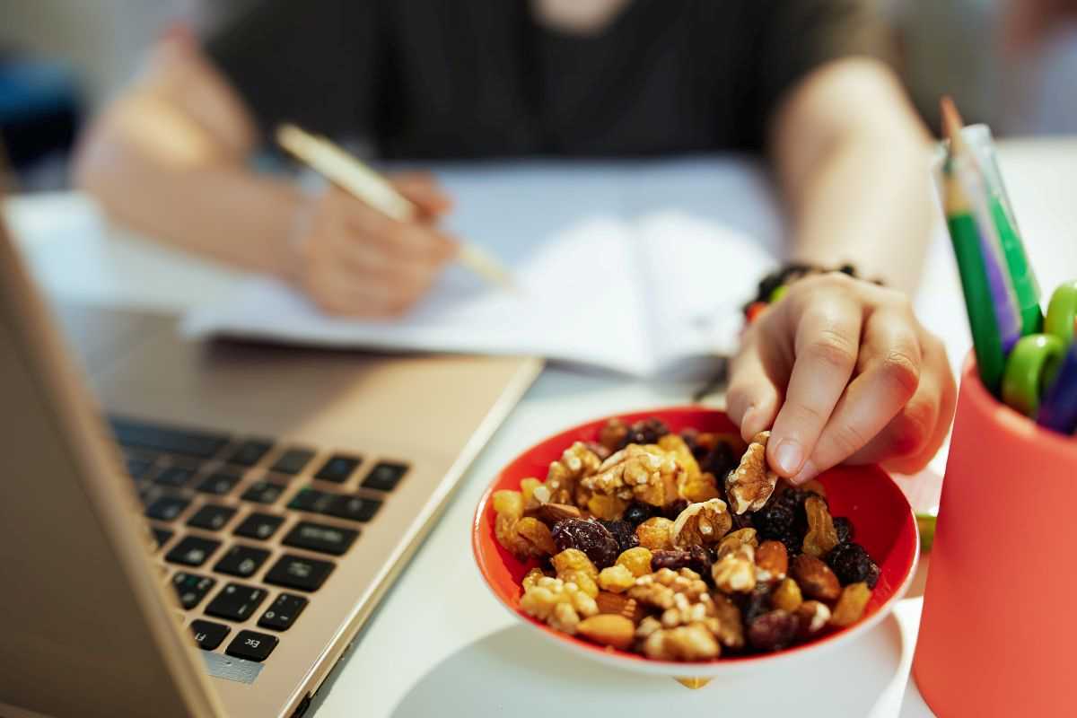 donna al computer che mangia frutta secca