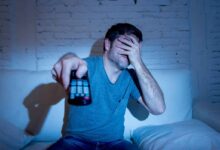 un uomo si copre gli occhi mentre guarda un film in televisione