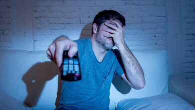un uomo si copre gli occhi mentre guarda un film in televisione