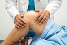 medico che tasta il ginocchio di un paziente sdraiato sul lettino