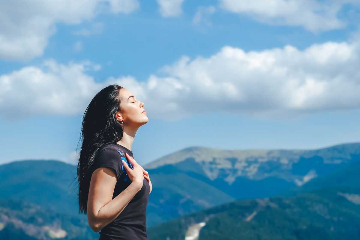 ragazza che respira a pieni polmoni in montagna