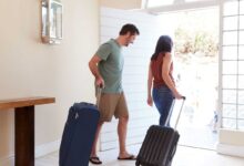 coppia che lascia la casa con le valigie perché sono in partenza per le vacanze
