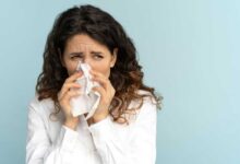 donna con rinite e allergia respiratoria mentre starnutisce e si soffia il naso