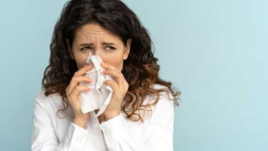 donna con rinite e allergia respiratoria mentre starnutisce e si soffia il naso