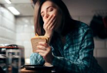 donna con sindrome du cushing che presenta stanchezza cronica e sbadiglia mentre mangia un panino