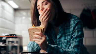 donna con sindrome du cushing che presenta stanchezza cronica e sbadiglia mentre mangia un panino