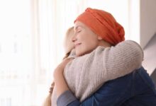 donna con tumore, con turbante in testa, abbraccia un'altra donna
