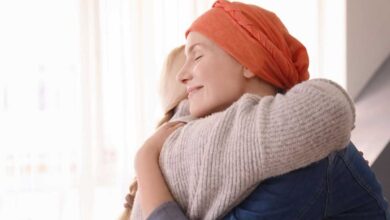 donna con tumore, con turbante in testa, abbraccia un'altra donna