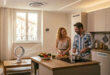 coppia che cucina in casa mentre si raffresca con un ventilatore senza pale