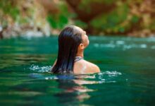 donna che nuota in acque naturali praticando wild swimming
