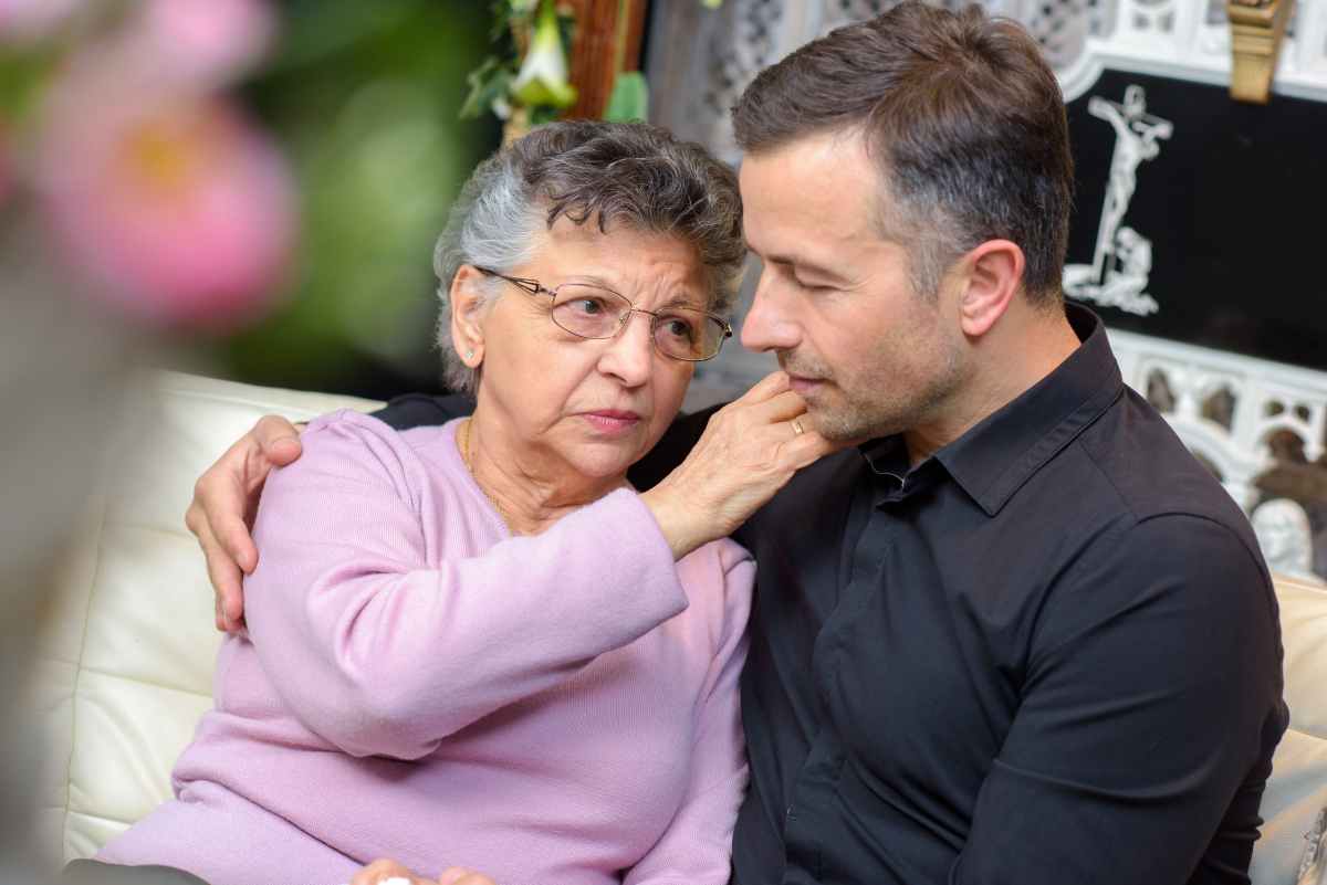 una anziana madre accarezza il figlio