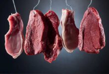 diversi tagli di carne appesa a ganci di metallo