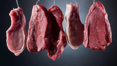 diversi tagli di carne appesa a ganci di metallo
