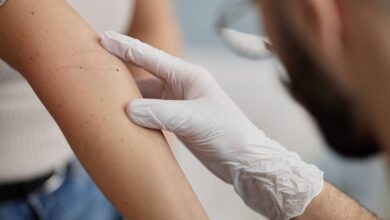 un dermatologo controlla i nei sul braccio di una paziente