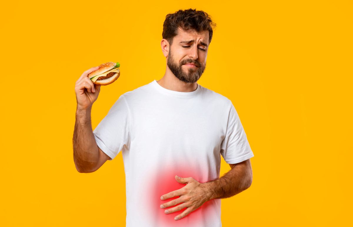 un ragazzo con un hamburger in mano ha mal di pancia