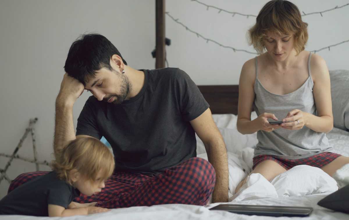 una coppia di genitori stanca sul letto insieme al figlio