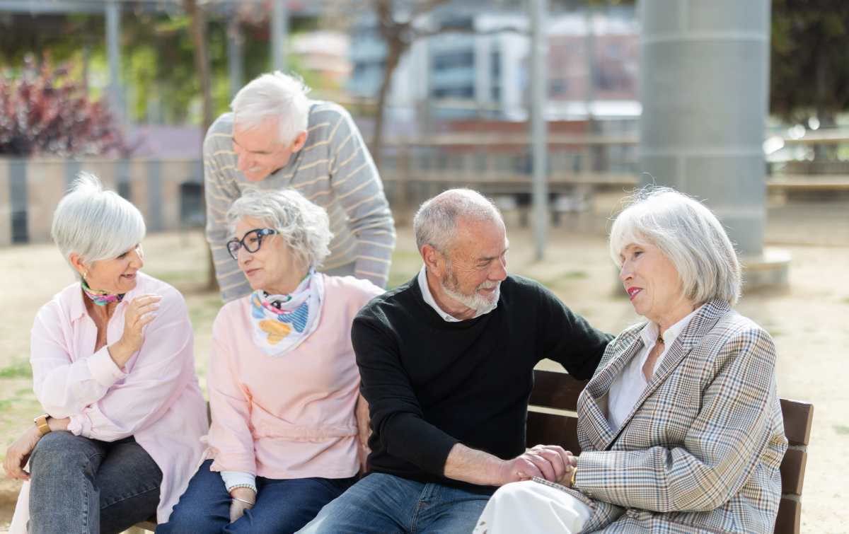 un gruppo di sessantenni discute su una panchina