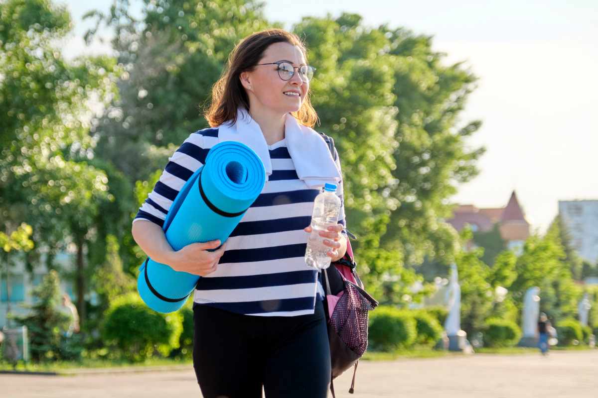 una donna passeggia con il tappetino da yoga 