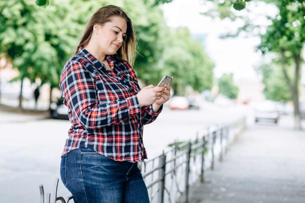 una ragazza curvy guarda sorridente verso il suo cellulare
