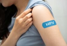 una ragazza mostra il cerotto sulla spalla con la scritta hpv