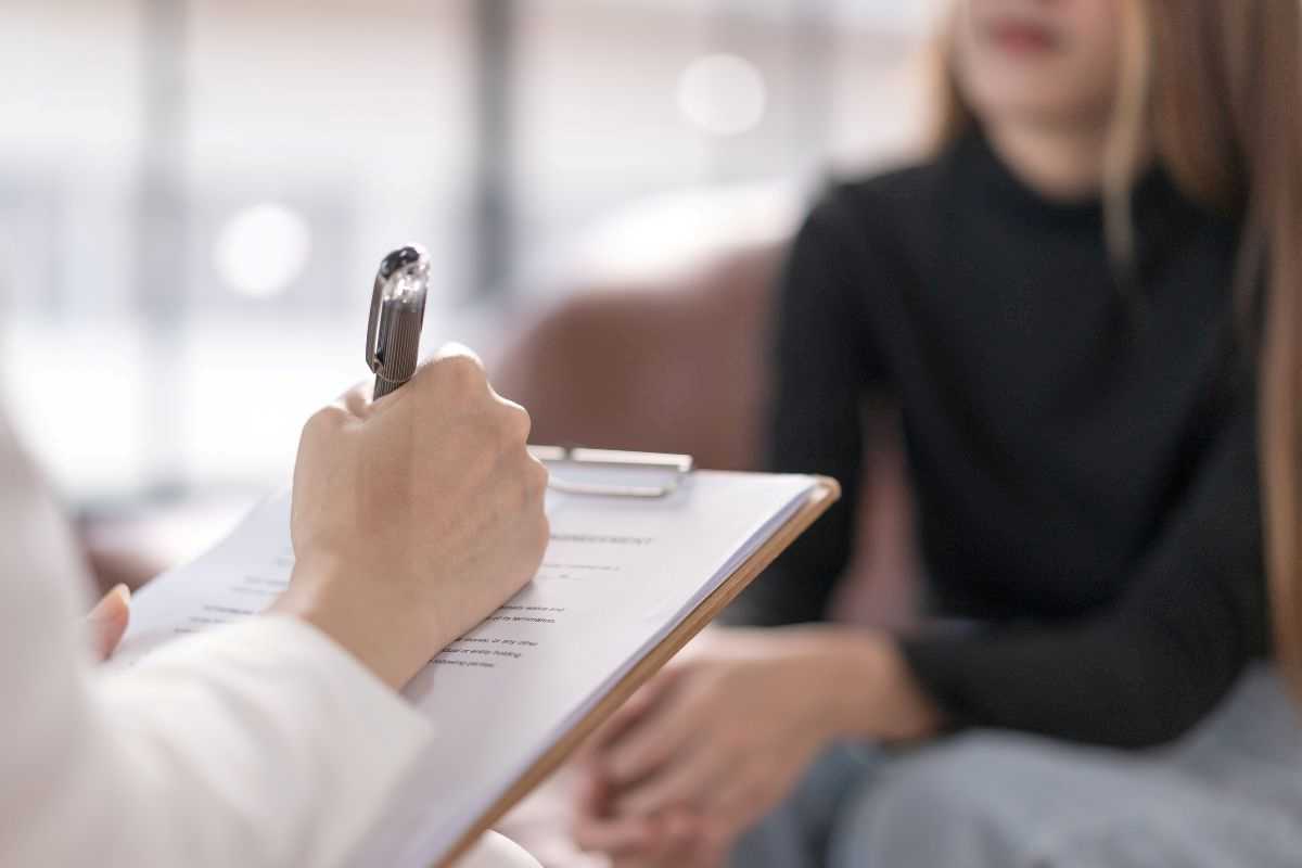 donna al consultorio mentre la dottoressa compila cartella clinica