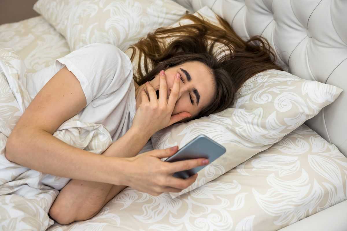 ragazza che controlla lo smartphone appena sveglia