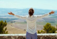 donna di spalle che guarda un panorama con le braccia aperte