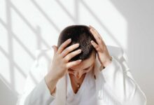 donna in ufficio che si mette le mani sul capo perché ha mal di testa