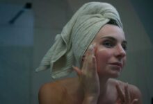 ragazza allo specchio che mette una crema idratante sulla pelle dopo l'estate