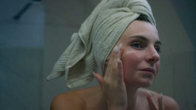 ragazza allo specchio che mette una crema idratante sulla pelle dopo l'estate