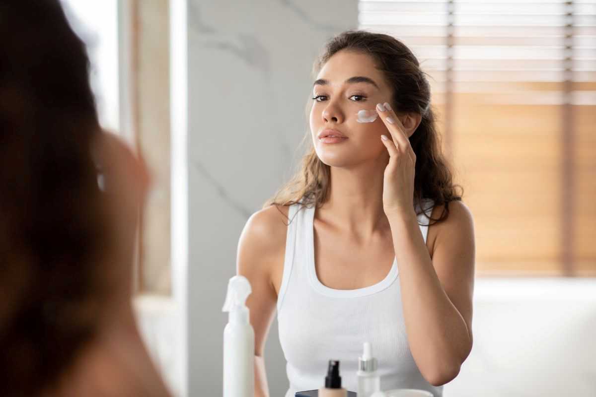 ragazza che applica crema idratante sul viso