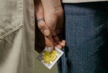 due persone che si stringono la mano e tengono un preservativo