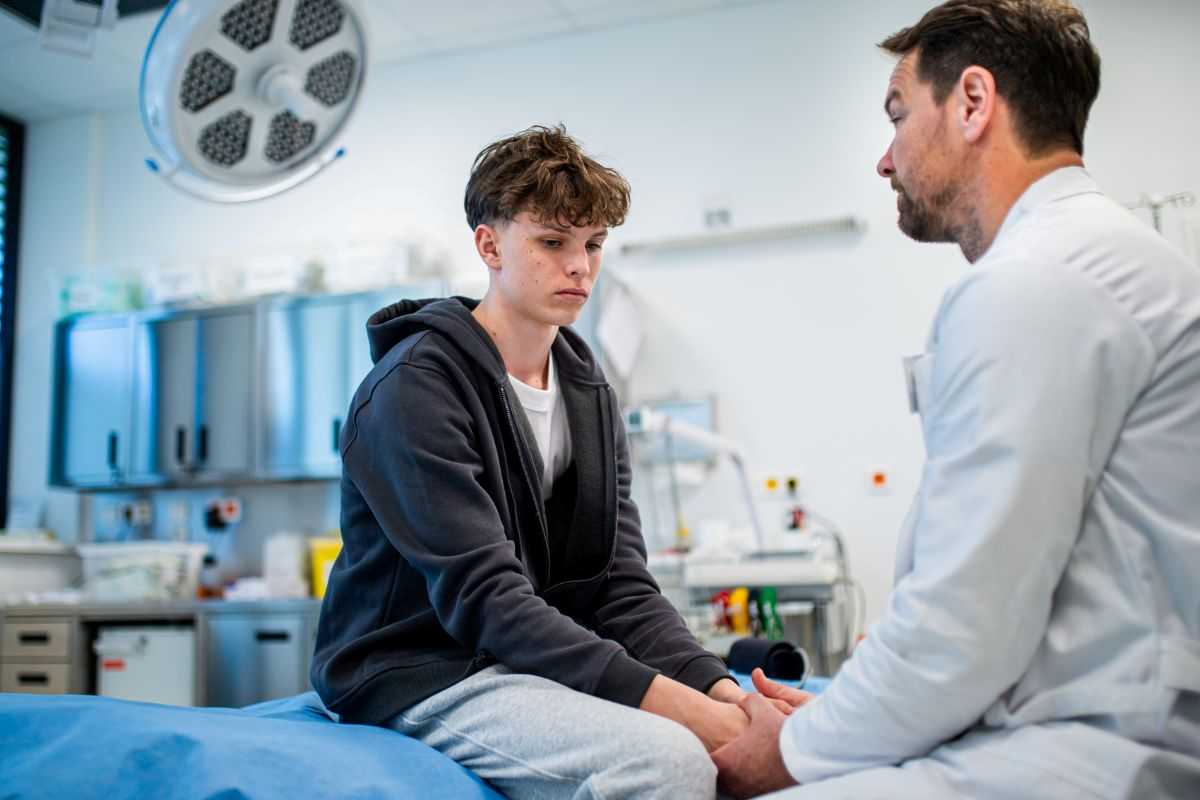 ragazzo giovane seduto sul lettino mentre il medico gli parla