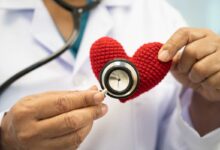 un medico ausculta un cuore di pezza con uno steteoscopio