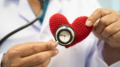 un medico ausculta un cuore di pezza con uno steteoscopio