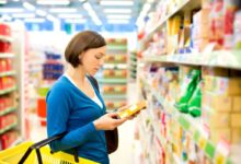 donna al supermercato che legge un'etichetta sulla confezione di un alimento per controllare i livelli di sale presente